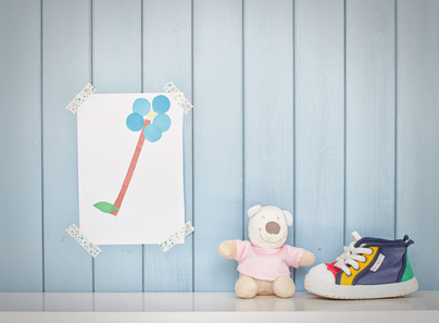 Funny colorful child picture on the wall in the room, tiny baby shoes and teddy bear toy