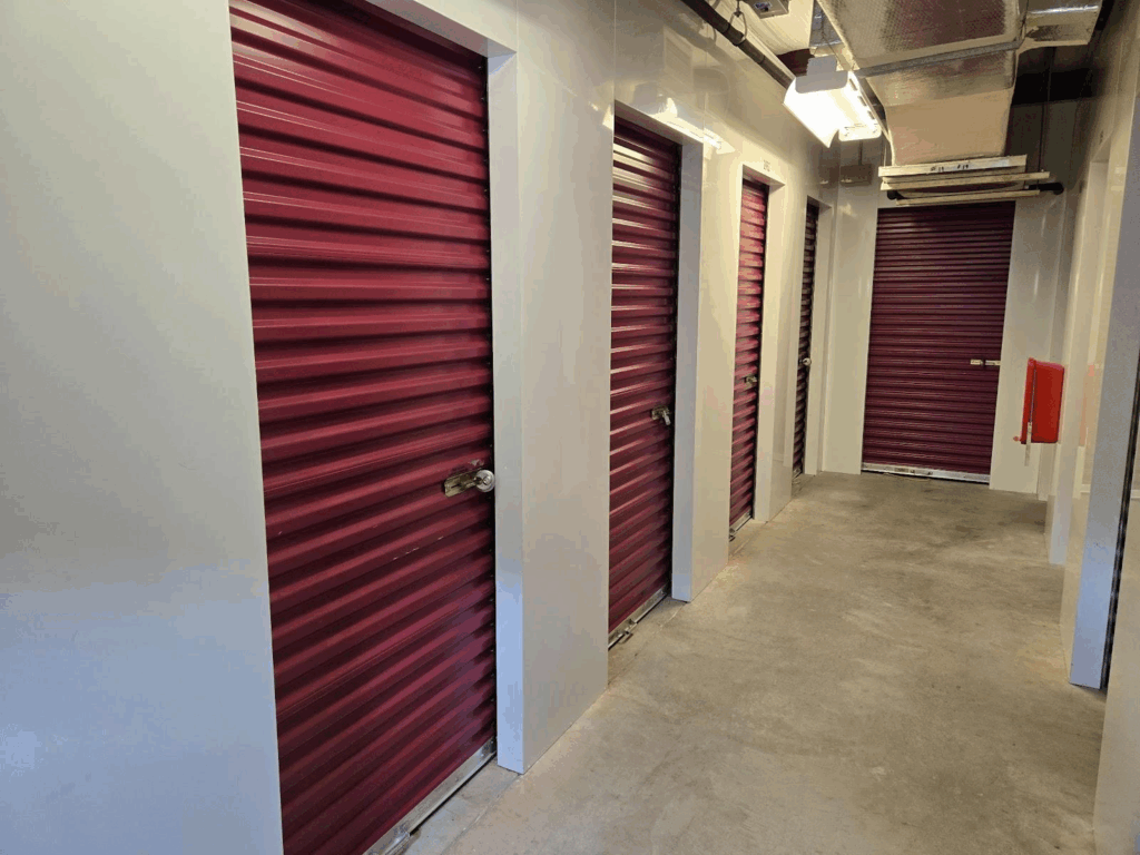 Interior hallway of a facility with multiple maroon roll-up doors, showcasing clean and secure climate controlled storage units