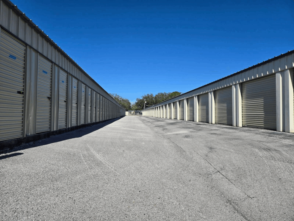  Outdoor rows of storage units with beige roll-up doors under a clear blue sky, providing secure and accessible climate controlled storage units for protecting belongings in various weather conditions
