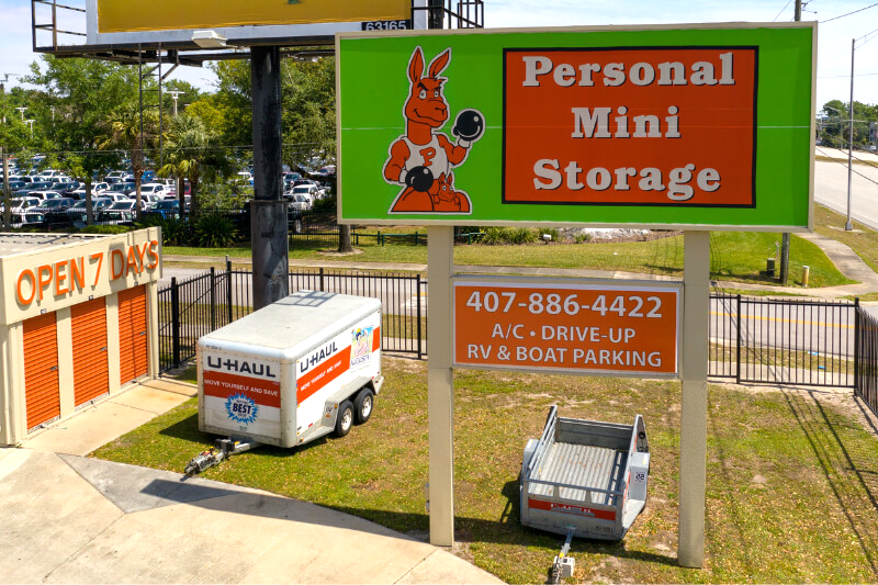 Outdoor view of Personal Mini Storage facility with a bright green and orange sign featuring a kangaroo mascot wearing boxing gloves